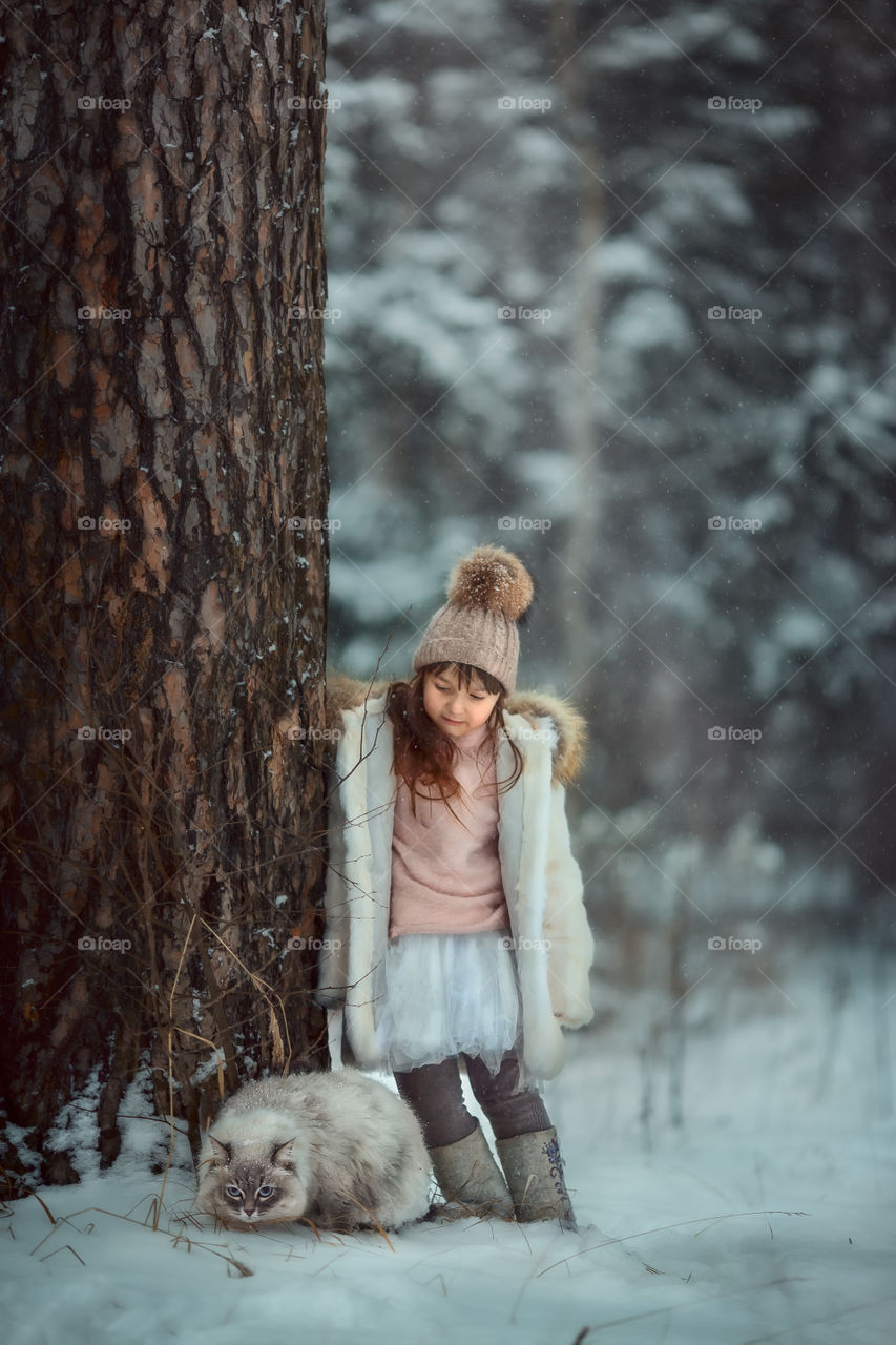 Winter forest at cloudy day. Little girl walking