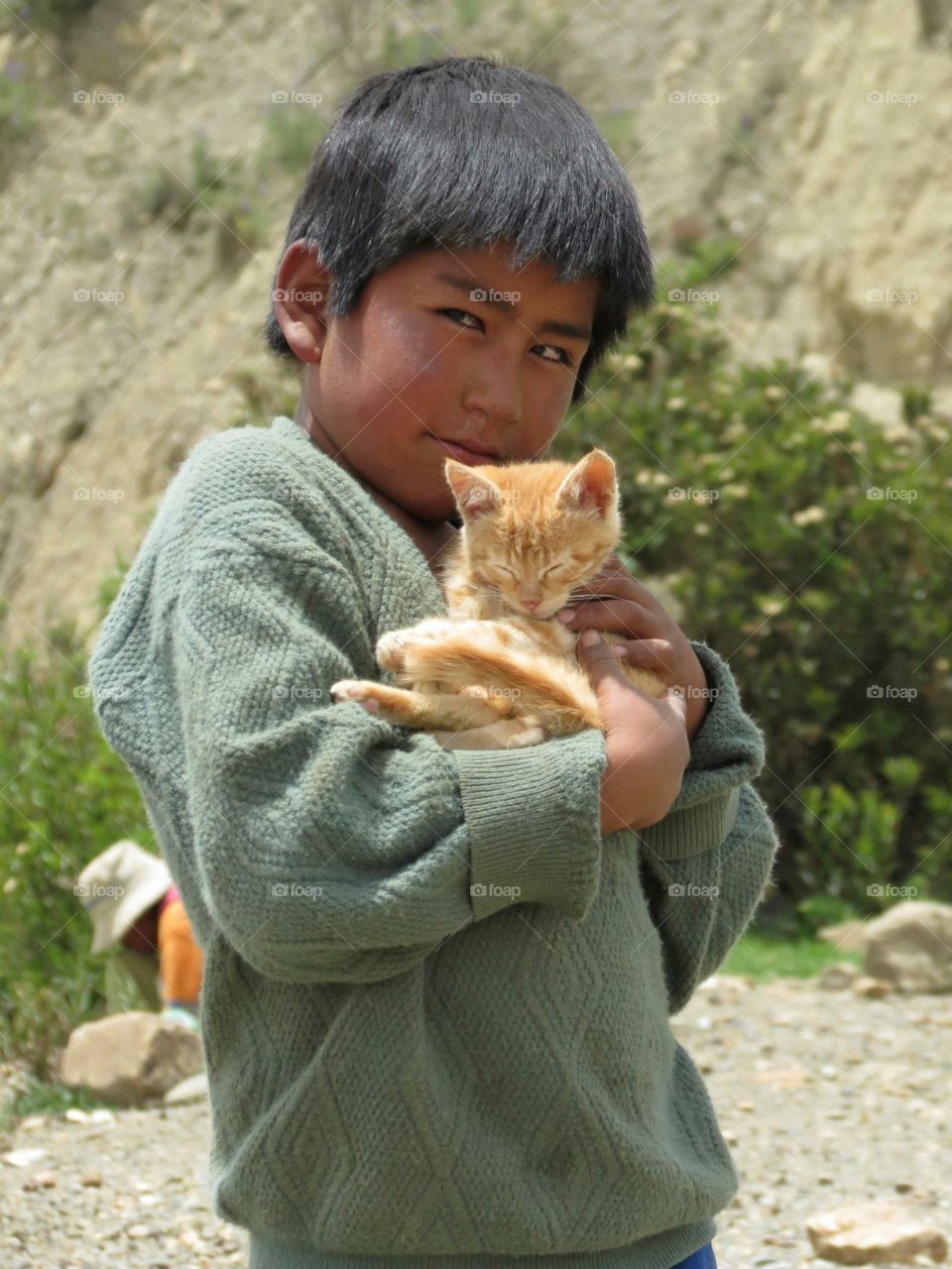 A young Bolivian boy hugging his pet kitten