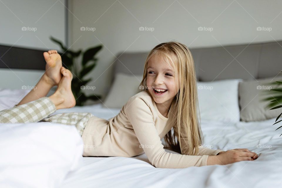 Happy little Caucasian girl with blonde hair in bed