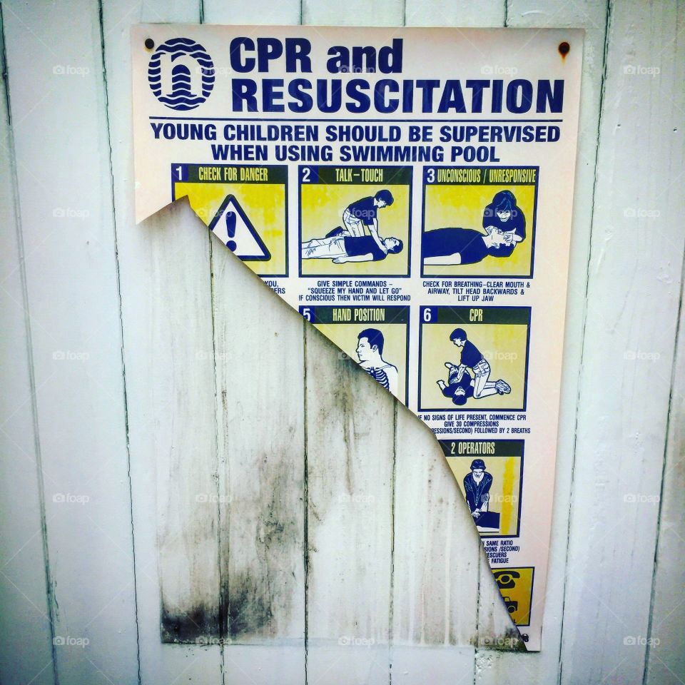 Ripped CPR resuscitation poster by a pool