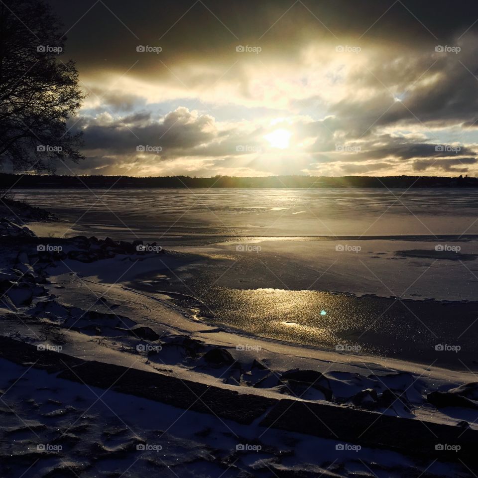 Beautiful sunset, darkness coming, Winter beach. Sun makes great contrast to the coastline. Icey lake reflect light and makes awesome view.
