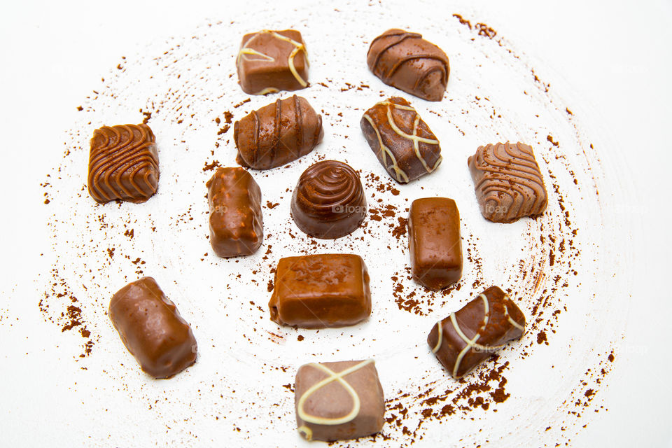 Different chocolates on swirled cocoa on a white background. Sweet sugar and candy close up