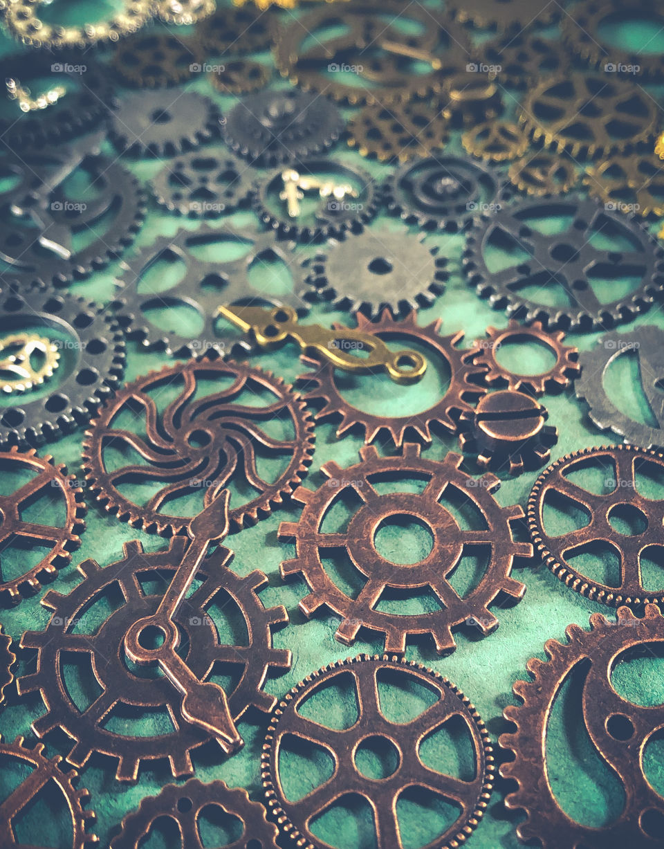 Copper, bronze and iron cogs laid out on a green background 