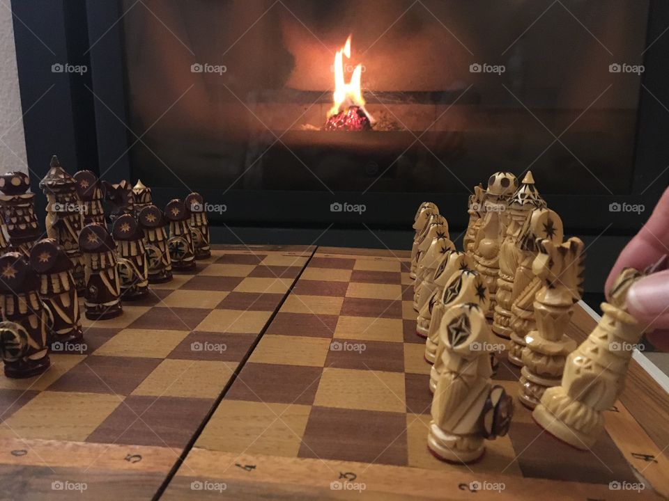 Preparing chessboard in front of fireplace at evening 