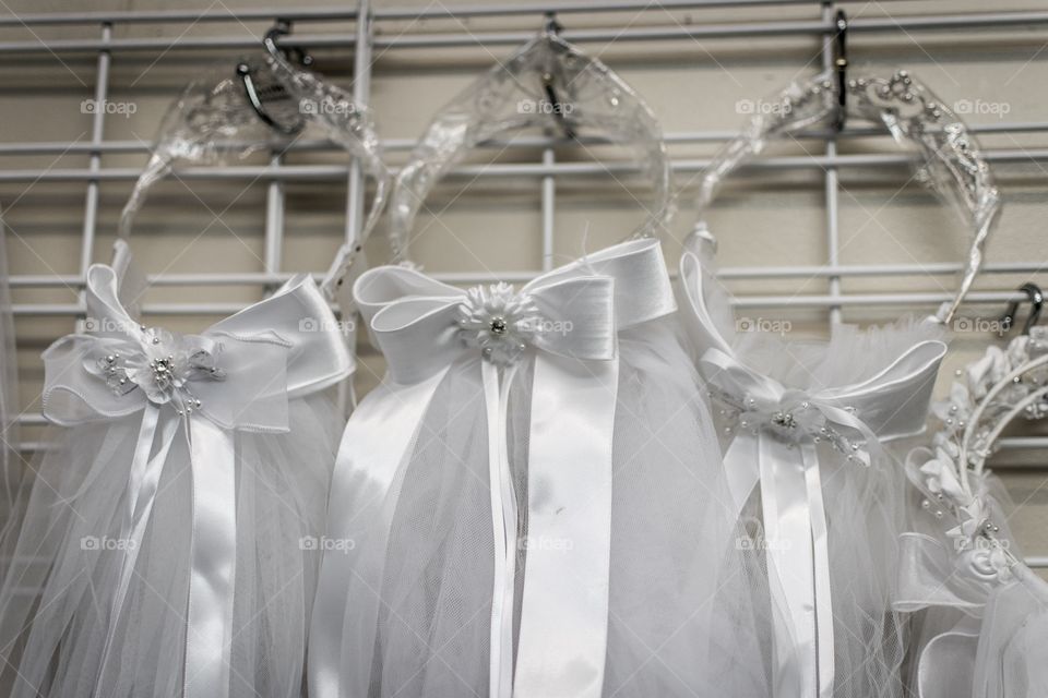 Three pretty, white, beribboned veils intended to be sold to young girls going through the Roman Catholic sacrament of first communion.