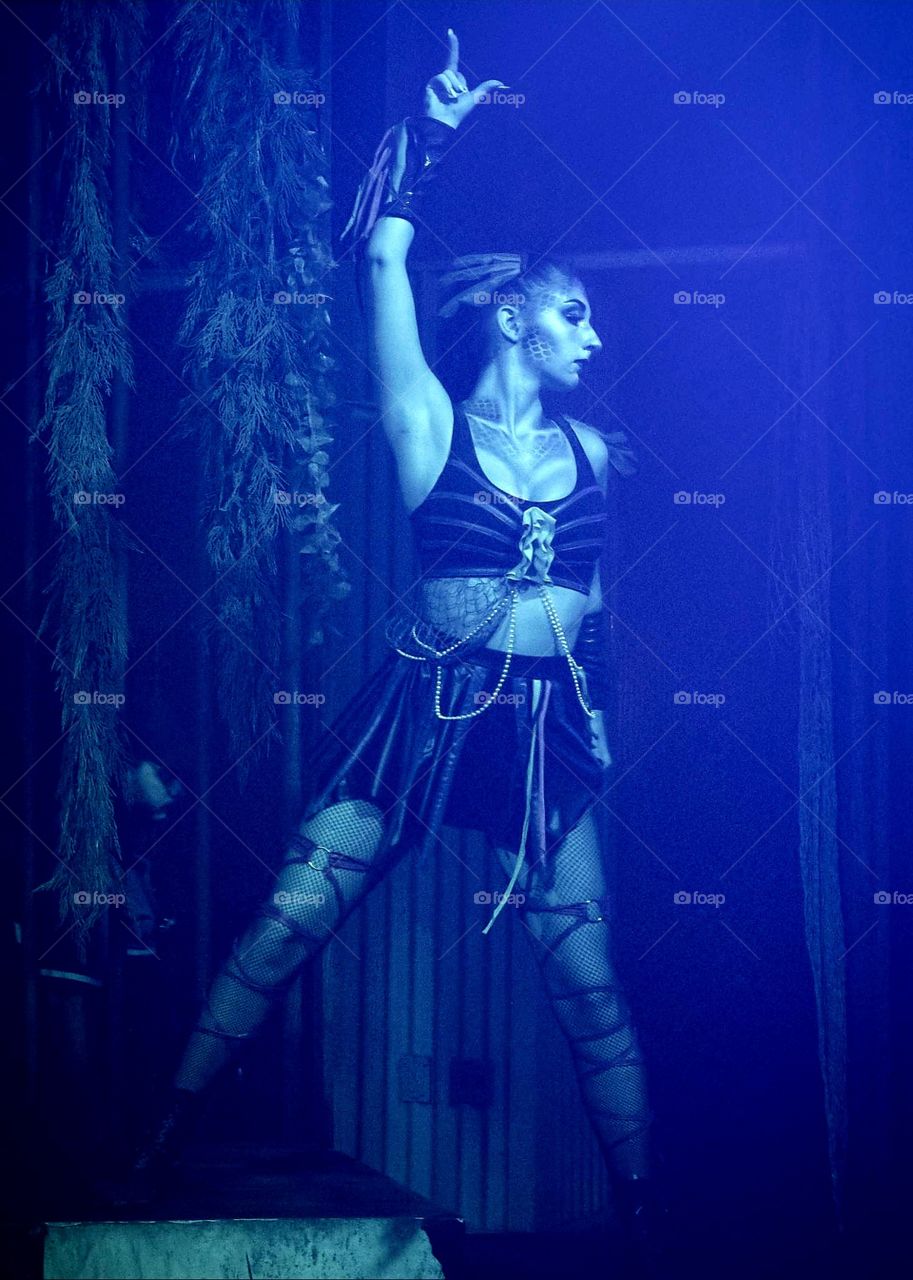 beautiful sexy zombie go-go dancer moving and posing on a stage bathed in blue light