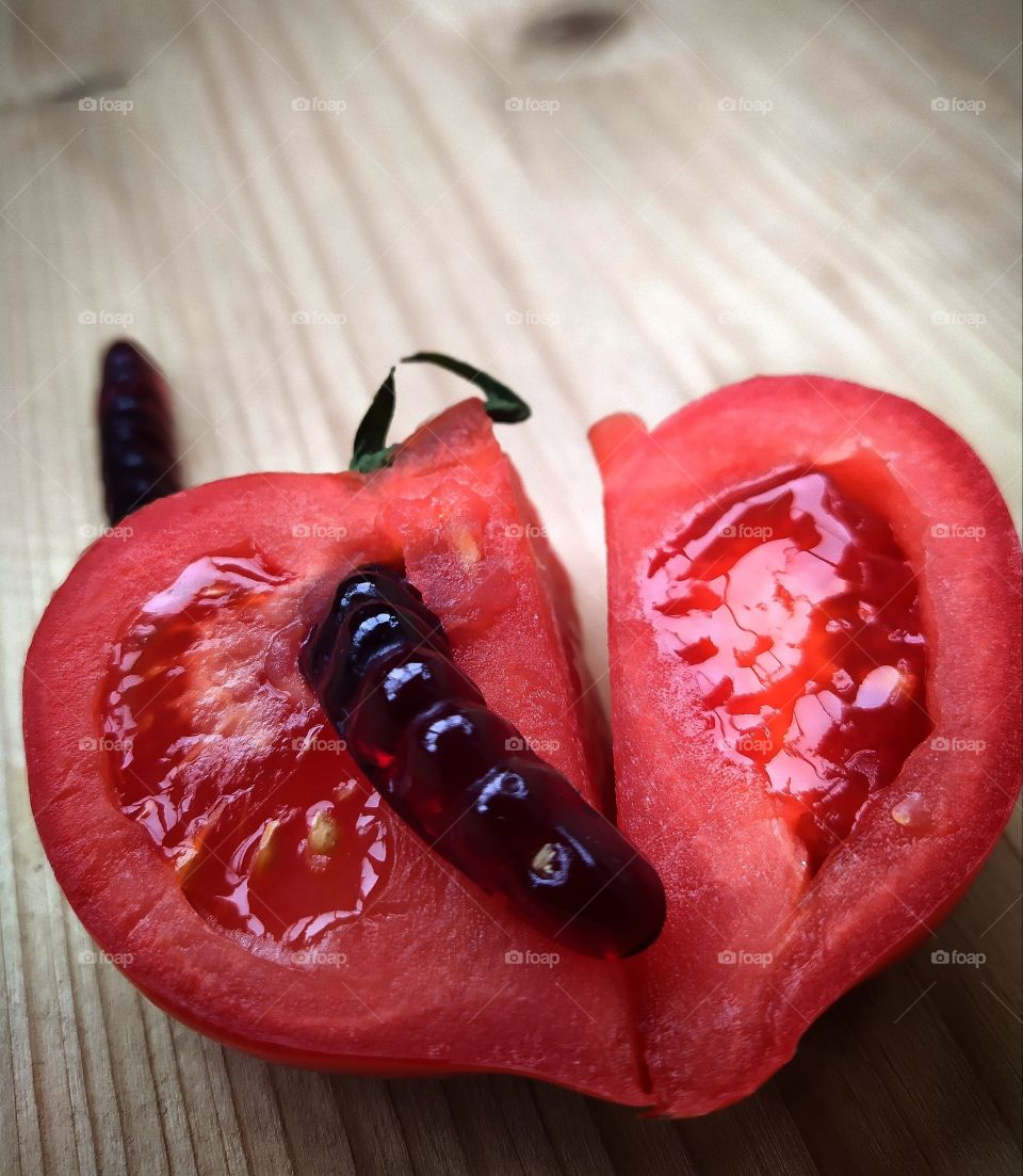Betrayal.  A heart-shaped tomato that is split in half.  On one half of the tomato there is a worm