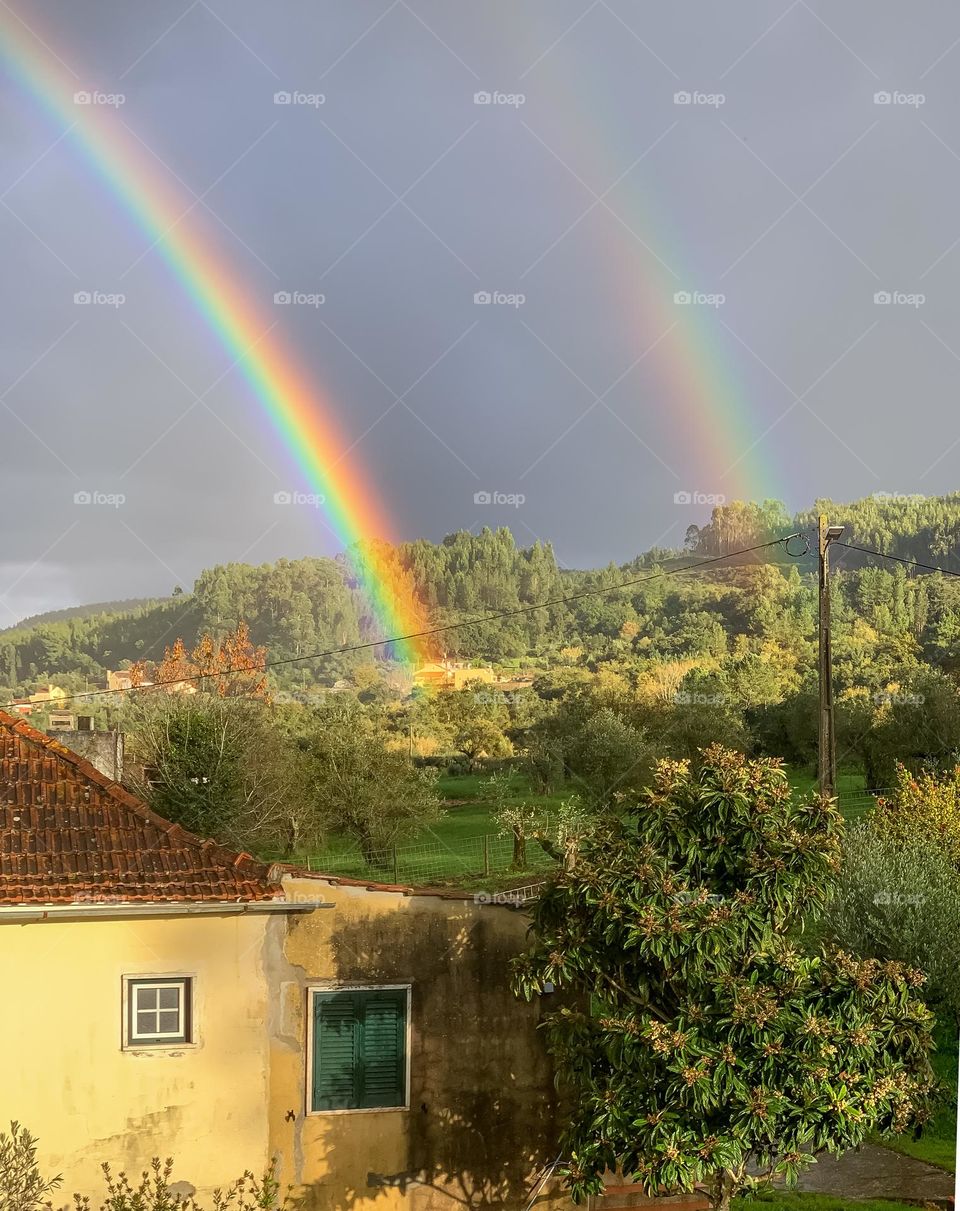 A happy, double rainbow creates bright colours in the dark rain clouds