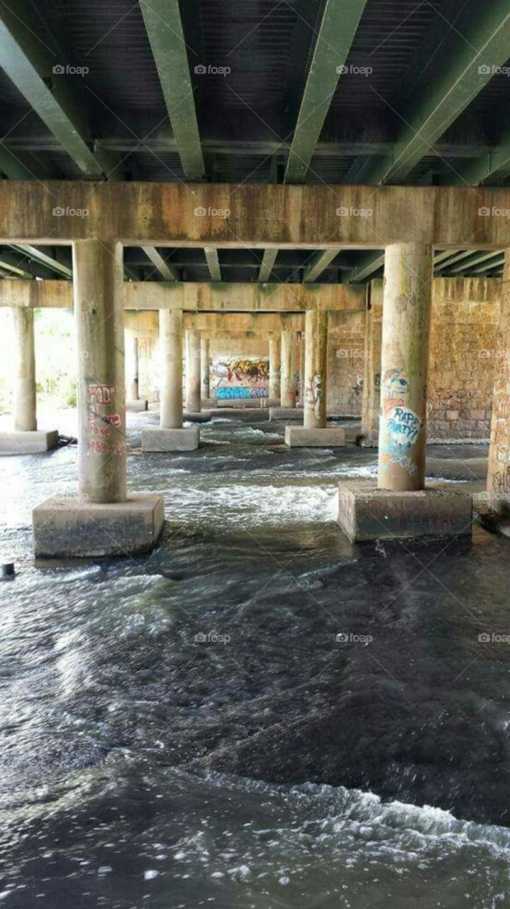 River under bridge with graffitti