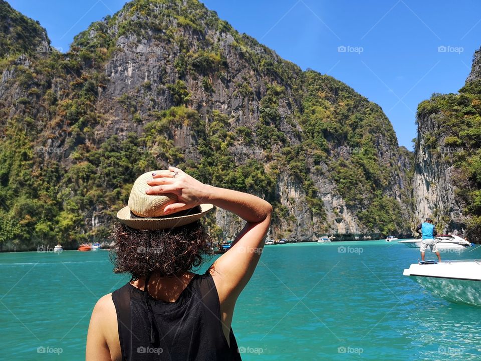 Woman with shoulders with hat observes the sea on phi phi island