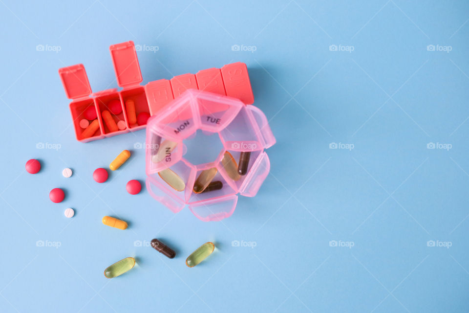 Pink boxes with pills and capsules on the blue background top view