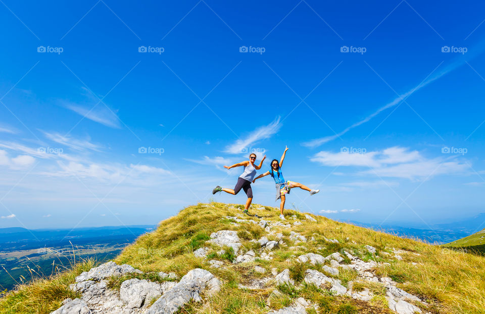 Teenage girl and woman having fun on top of mountain