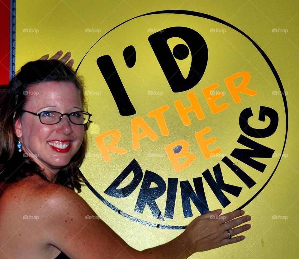 Woman with sign saying "I'd rather be drinking!"