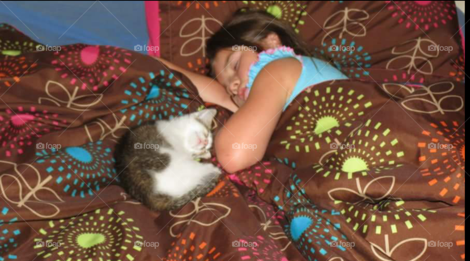 Small girl sleeping on bed with cat