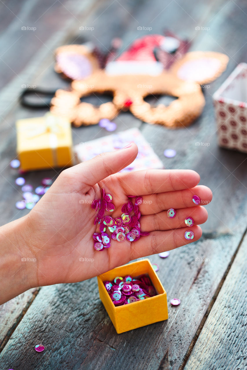 Girl decorating Christmas reindeer mask with sequins