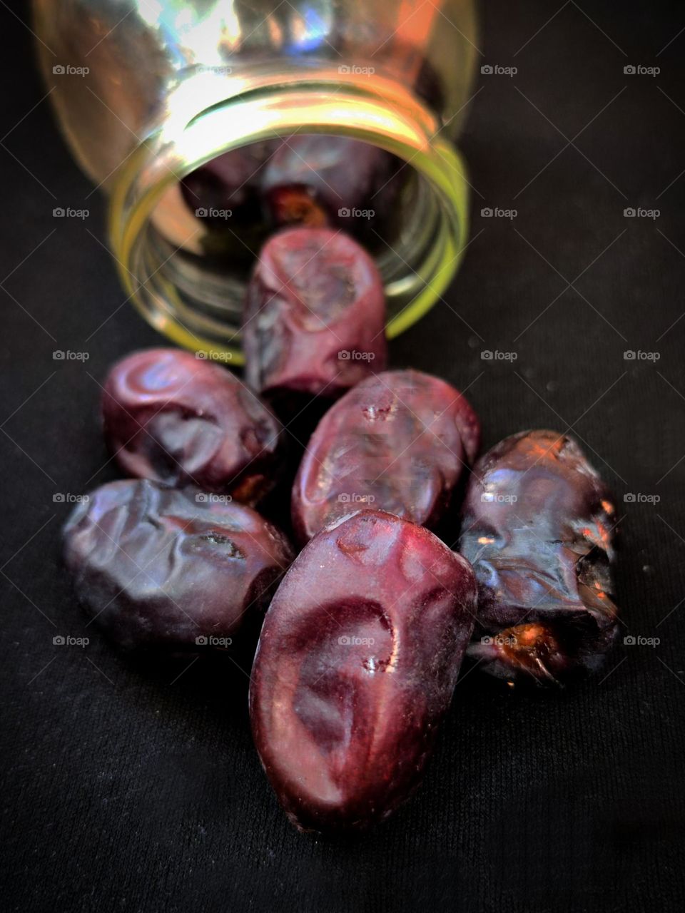 Dates spilled out of a jar on a black background