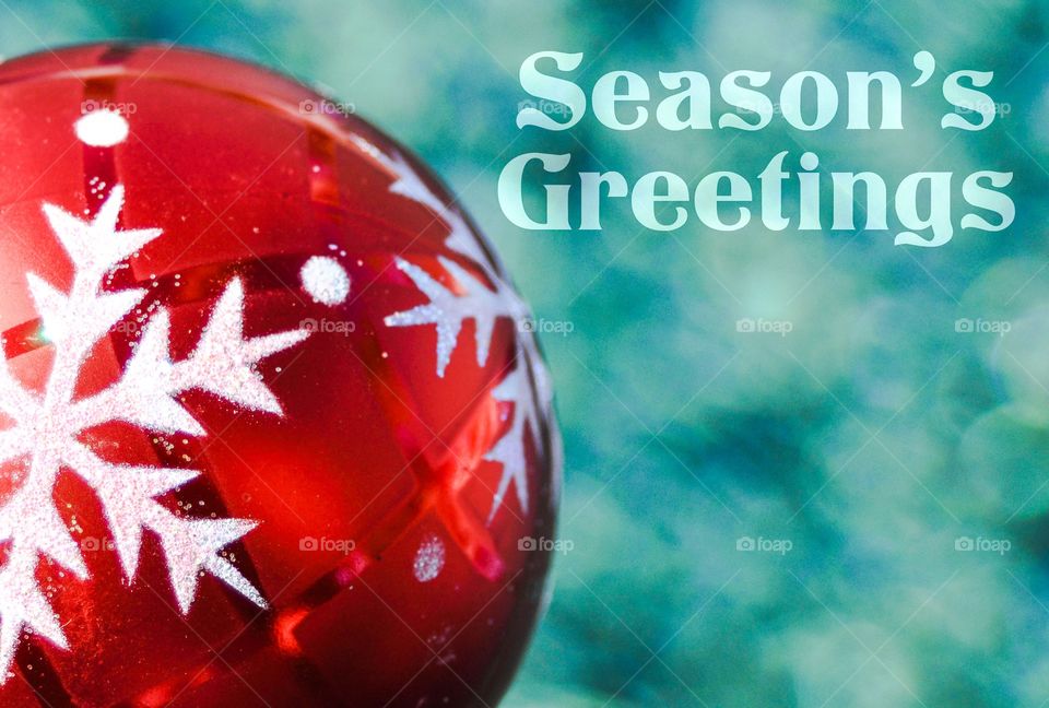 Christmas concept. Red Christmas tree ornament against a blue background with the words Season's Greeting. 
