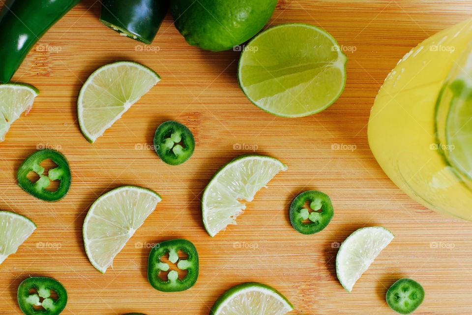 Flat lay of jalepeño pepper and lime with slices of each to flavor a quart-size mason jar of kombucha, all arranged on a bamboo cutting board