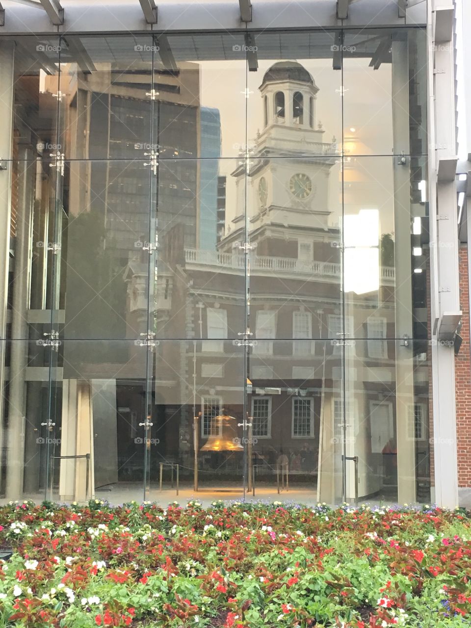 The Liberty Bell with Independence Hall reflected in the window.