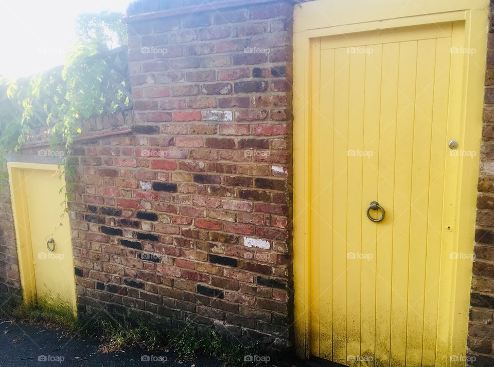 Big and little yellow doors at the side of a property in South Hill Park, Hampstead, London 