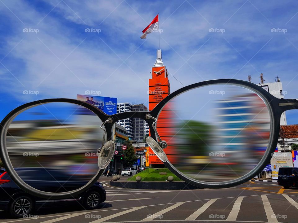 Behind the glasses car driver, Simpang Lima Monument is a monument to the Asian-African Conference, also known as the Bandung conference, which was held in April 1955, this red clock tower is 15 meter high and consists 11 squares