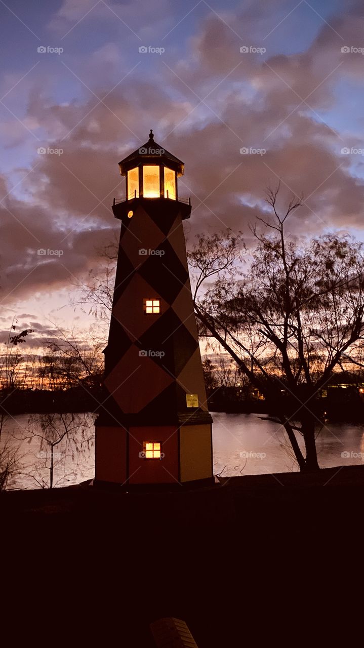 Evening sunset Reflective silhouette on Lake Water with lighthouse. Evening Colors timing for Sunset. Mostly Heavy Clouds building for Strong Weather Front Headed to this Region. 