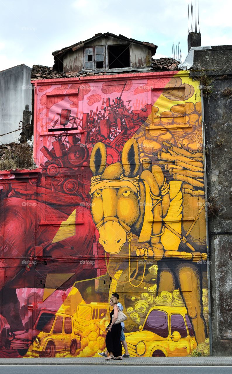 Young couple walking past a wall painting.