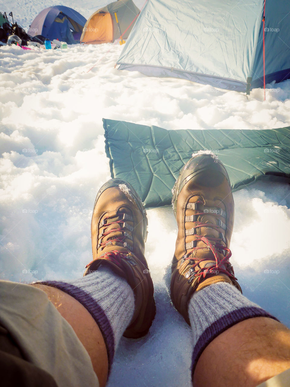 Man stretching out tired legs after mountain climbing 