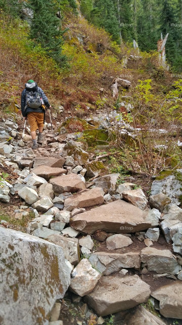 Man Hiking Rocky Trail. Solo hiker backpacking on rock path in Pacific Northwest mountains