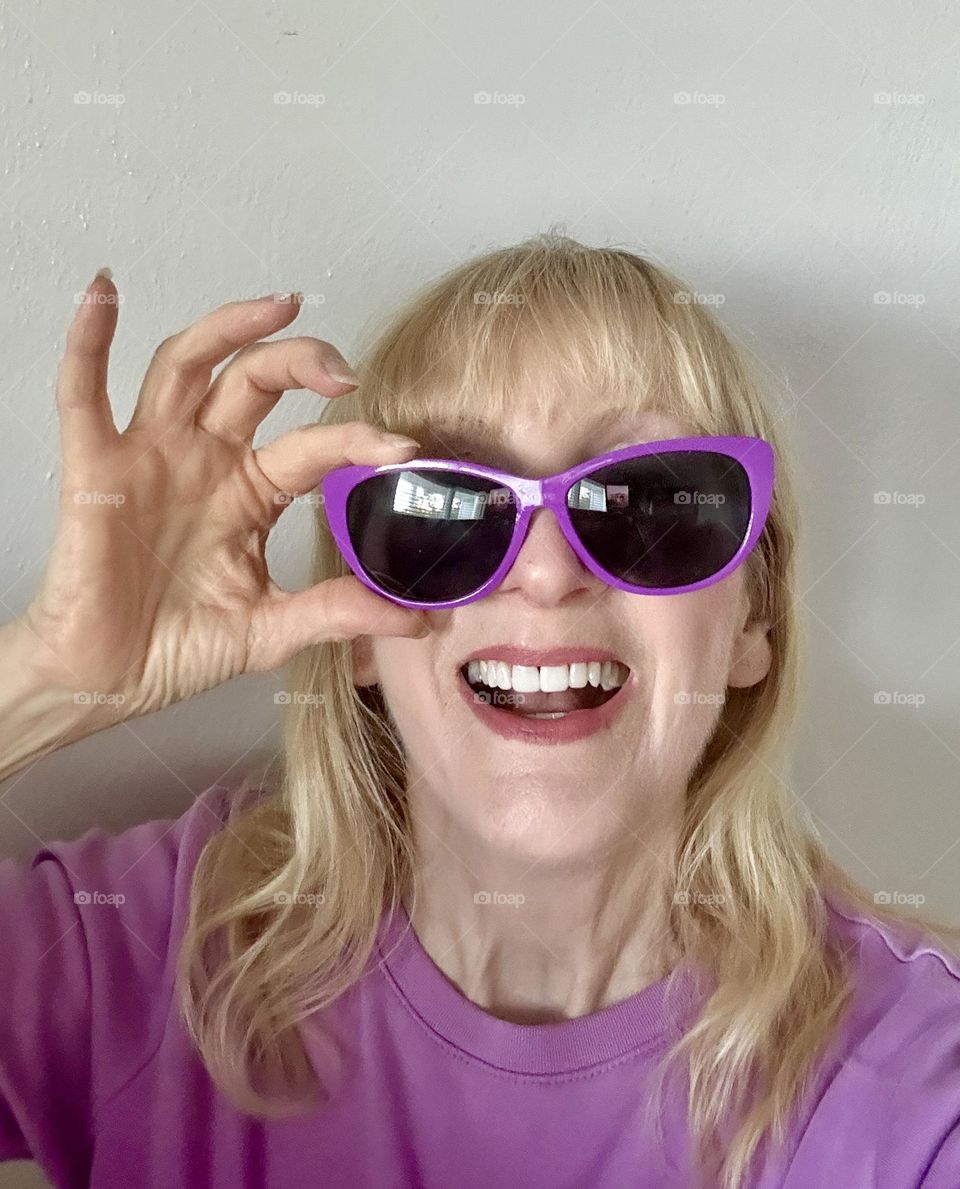 Woman laughing while putting on sunglasses 