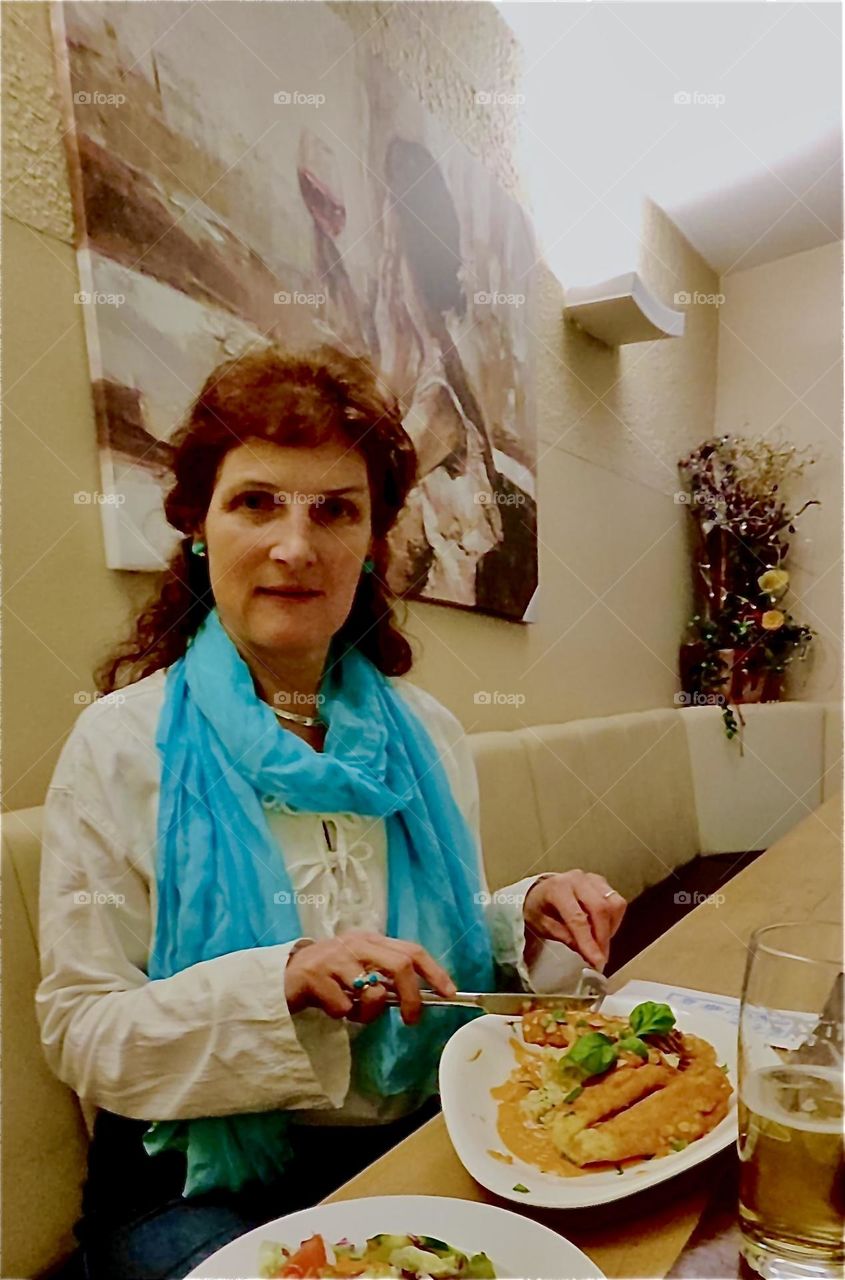 Enjoying lunch at a fashionable city café is one of the pastimes an elegant young lady likes to engage in and appreciate as is the case here at this restaurant in „Straubing“, „Niederbayern“ or „Lower Bavaria“, Germany. 2023. Hypnotic Productions