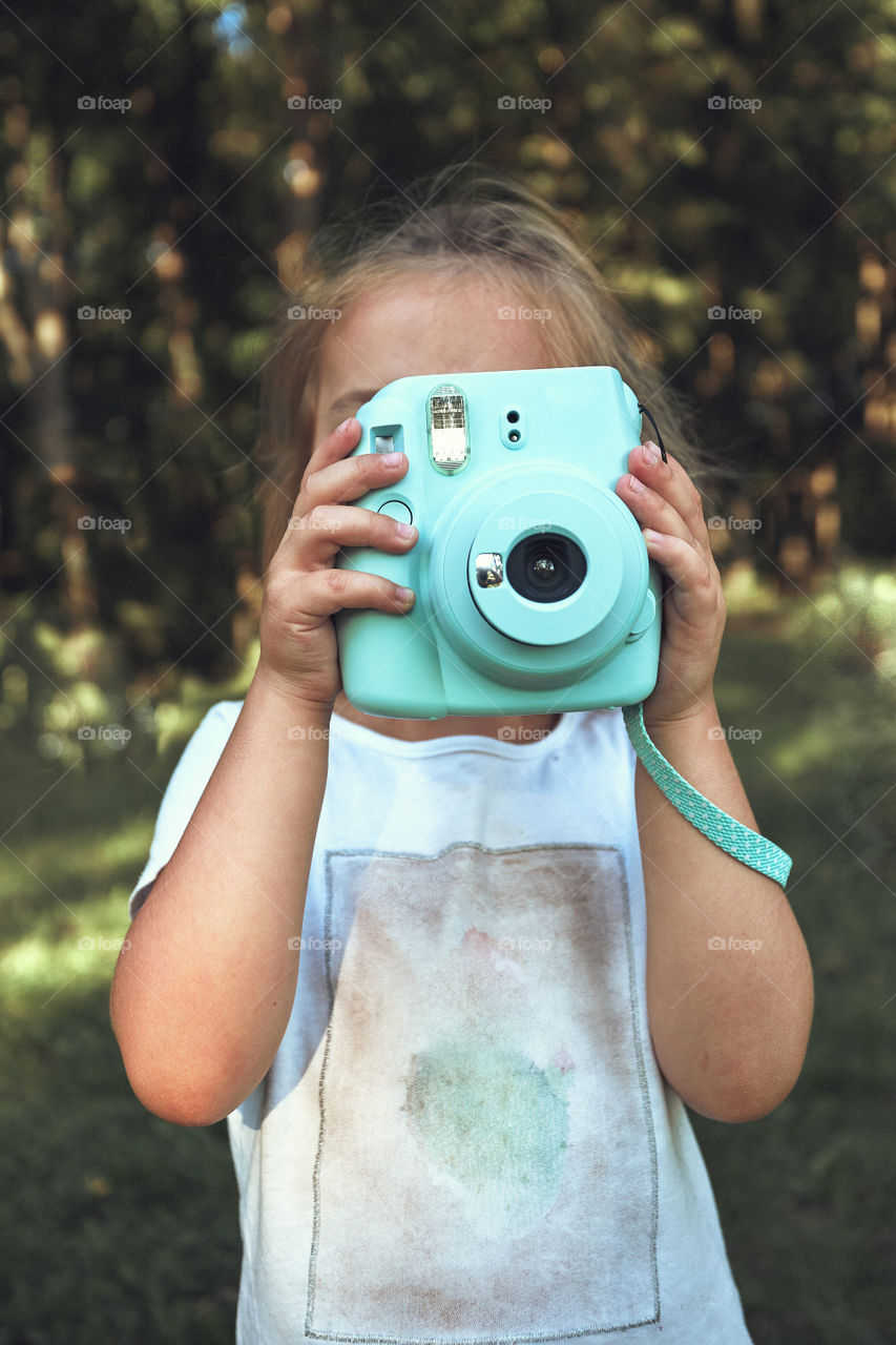 Little girl taking photo using instant camera. Candid people, real moments, authentic situations