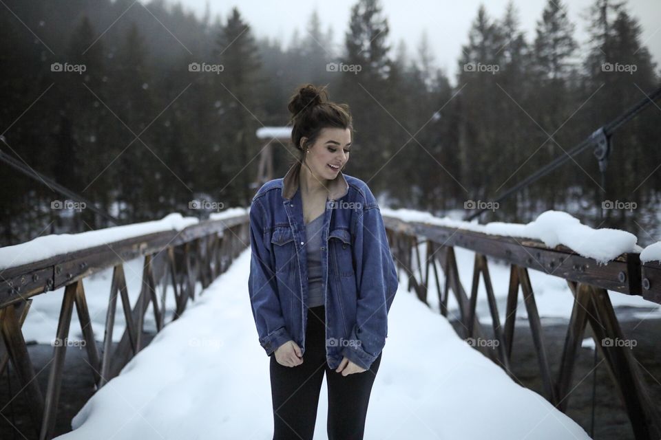 Girl in denim on a cold Montana day crossing a snow covered bridge. 