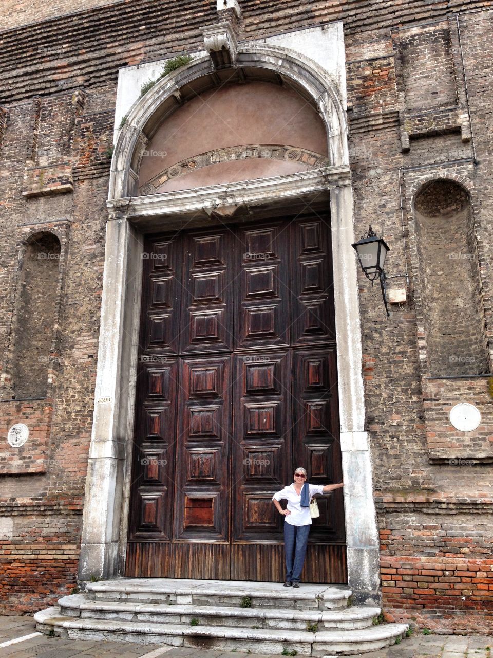 Mature woman standing in front of large wooden closed door