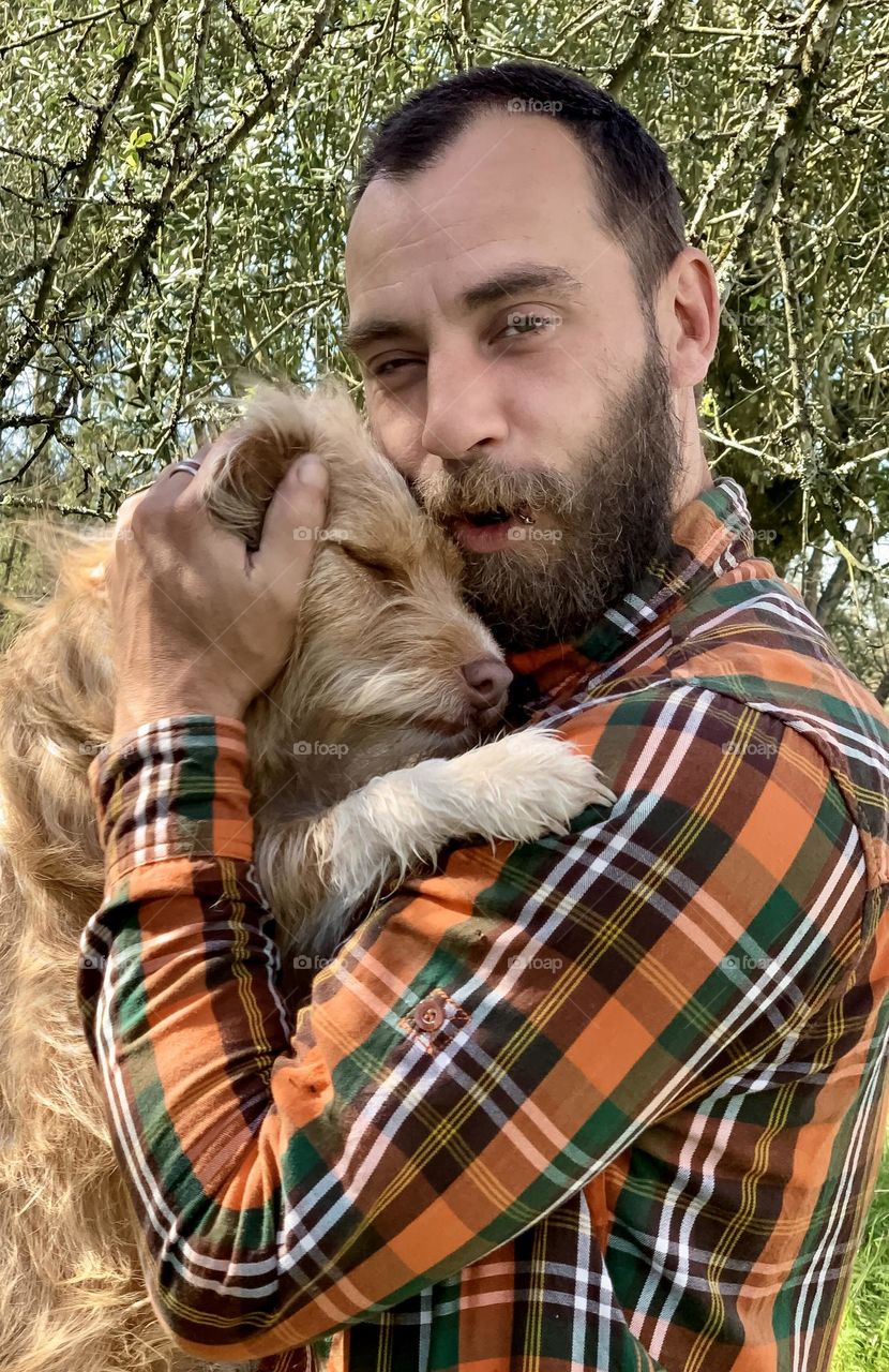 A man and his dog enjoy a precious moment of cuddle love.