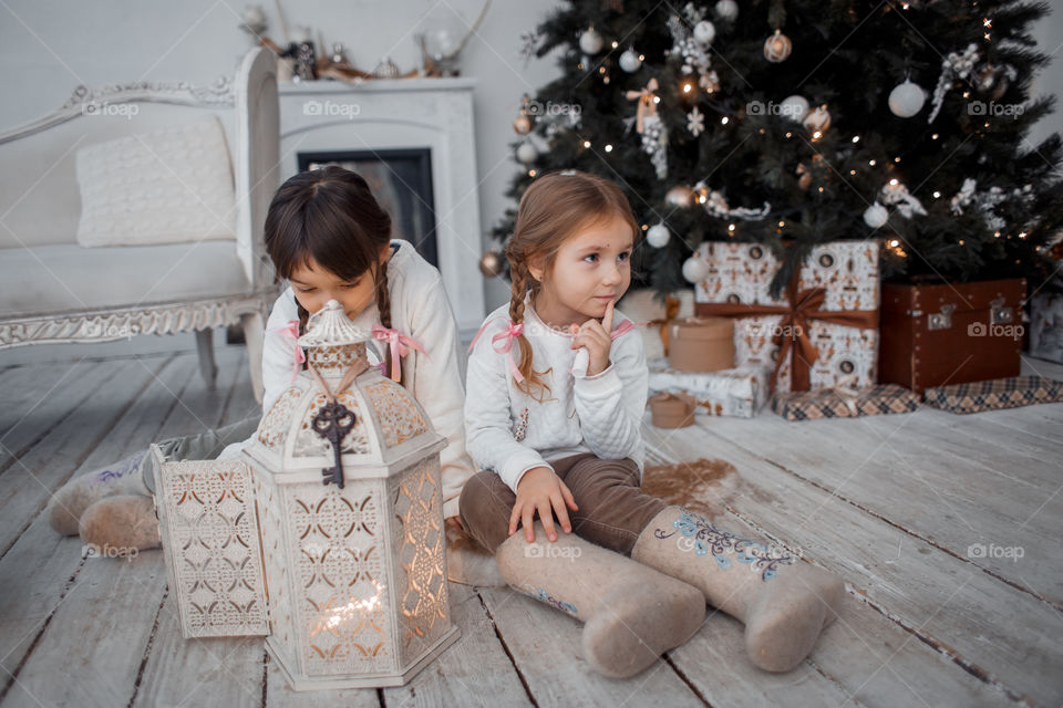 Little girls  in wool boots near Christmas tree 