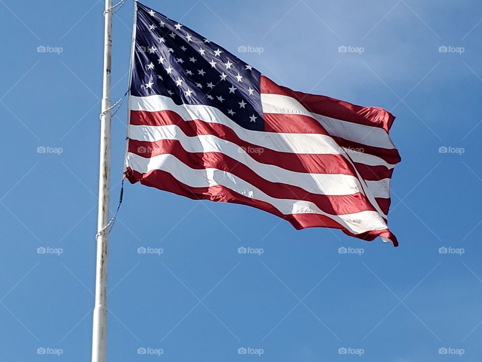 Large United States of a America flag with blue sky background