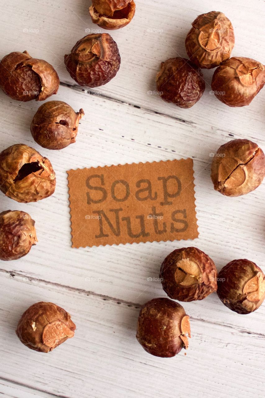 Soap nuts or soap berries on weathered white wooden background with identification placard in natural light