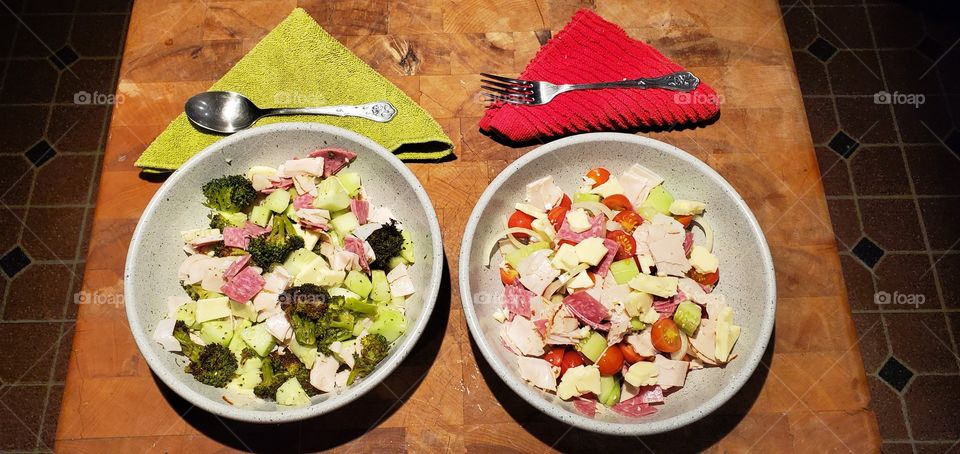 Salads in bowls, ready to eat, serving two different types of salads. Napkins, forks, lunch or supper.