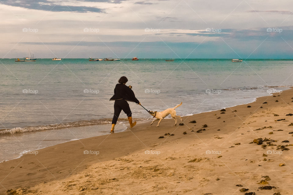 Girl with her dog playing and having fun on the red crown beach Bahia Brazil