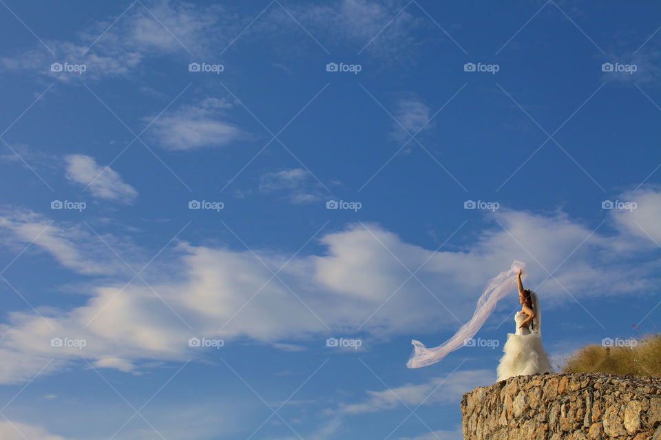 Bride near cliff in a windy sunny day
