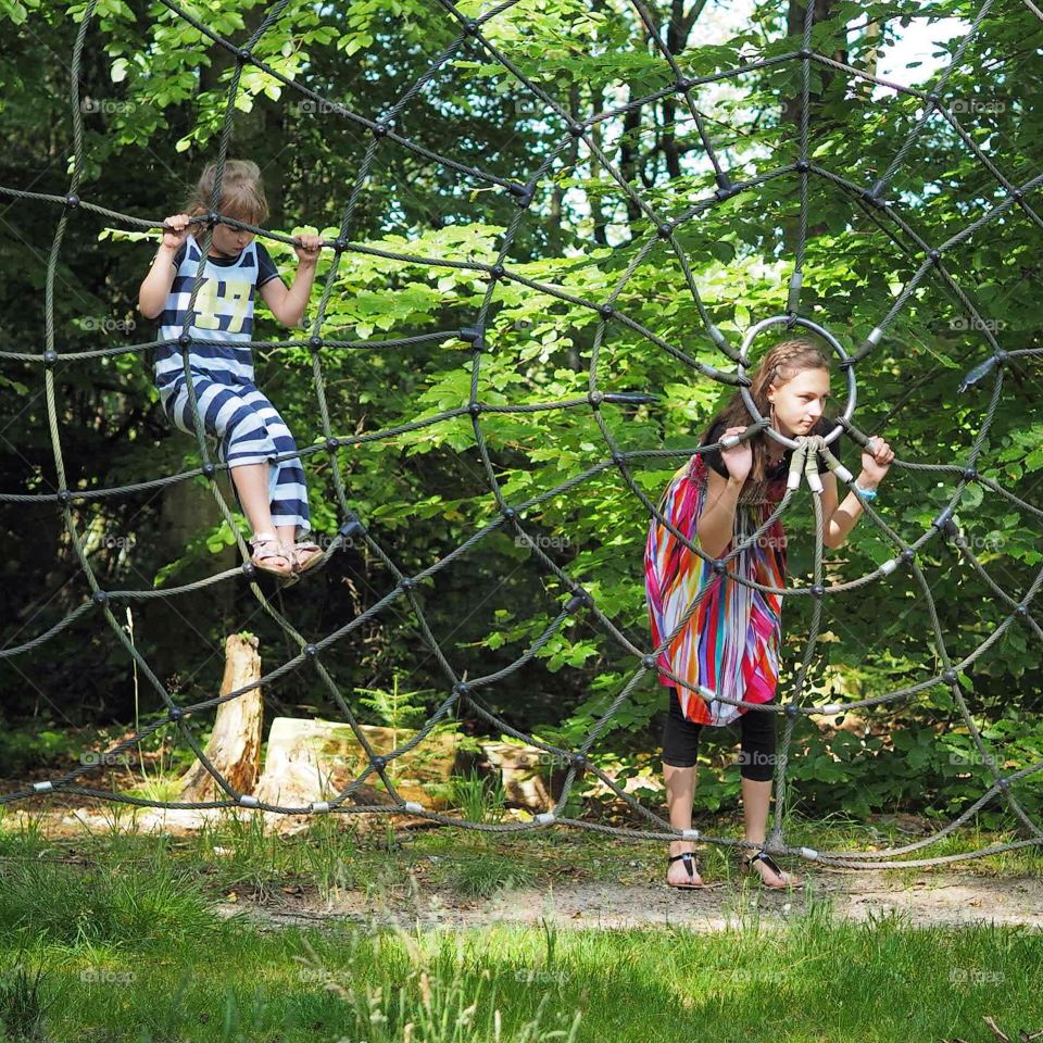 Playing in spiders web. Two girls playing in giant spiders web in a park