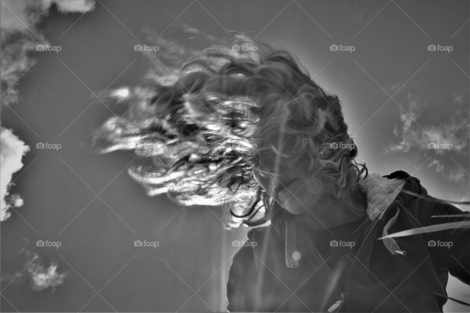 black and white dynamic picture of woman waving her curly hair in the wind and sun