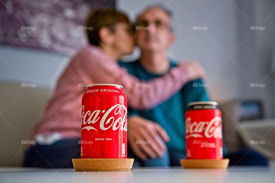 Couple watching television with two cokes