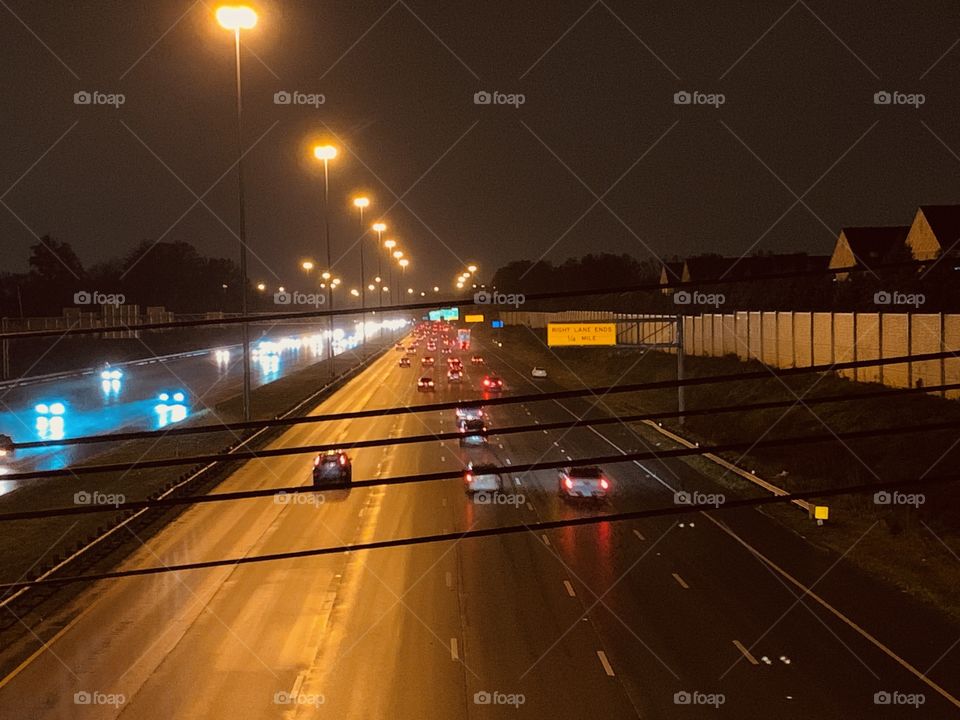 After dark, in the Midwest. A look down onto the Highway, from a city bridge. It’s raining.