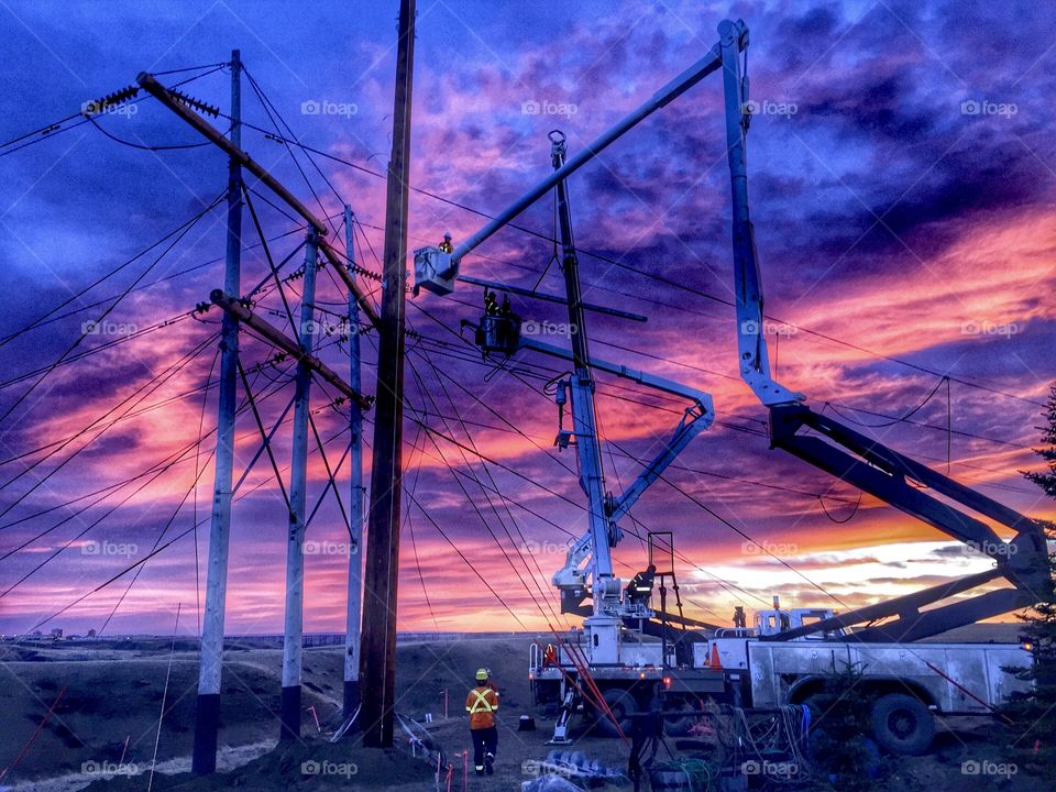 Powerline workers and Intense storm sunset 