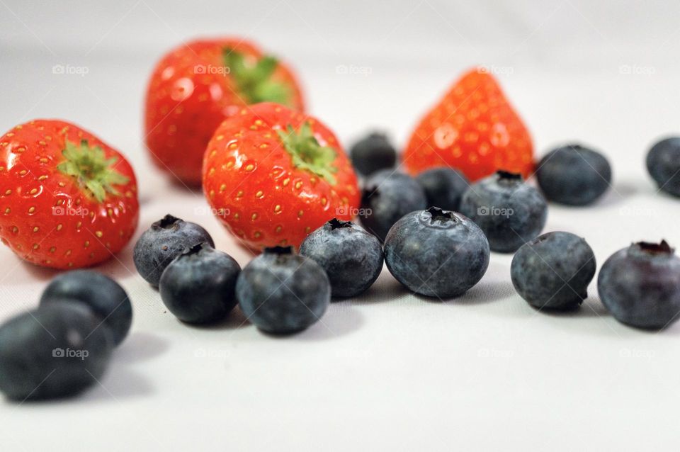 Close up of strawberries and blueberries. Blue and red colors on a white background