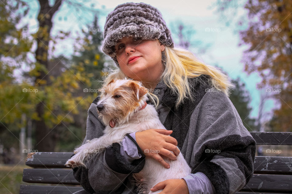 A portrait of a woman with a cap in a gray cape and Jack Russell terrier dog