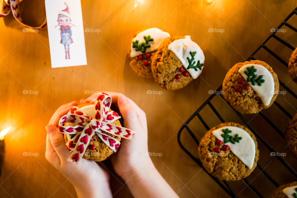 The gift of homemade Christmas biscuits - so special! Image of girl holding cookies tied with ribbon in heart shape.