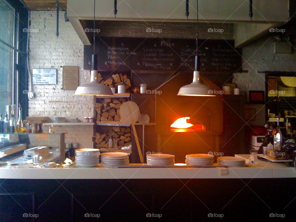Brick oven ambience. Fire from a brick oven illuminates a restaurant kitchen on the Lower East Side of Manhattan